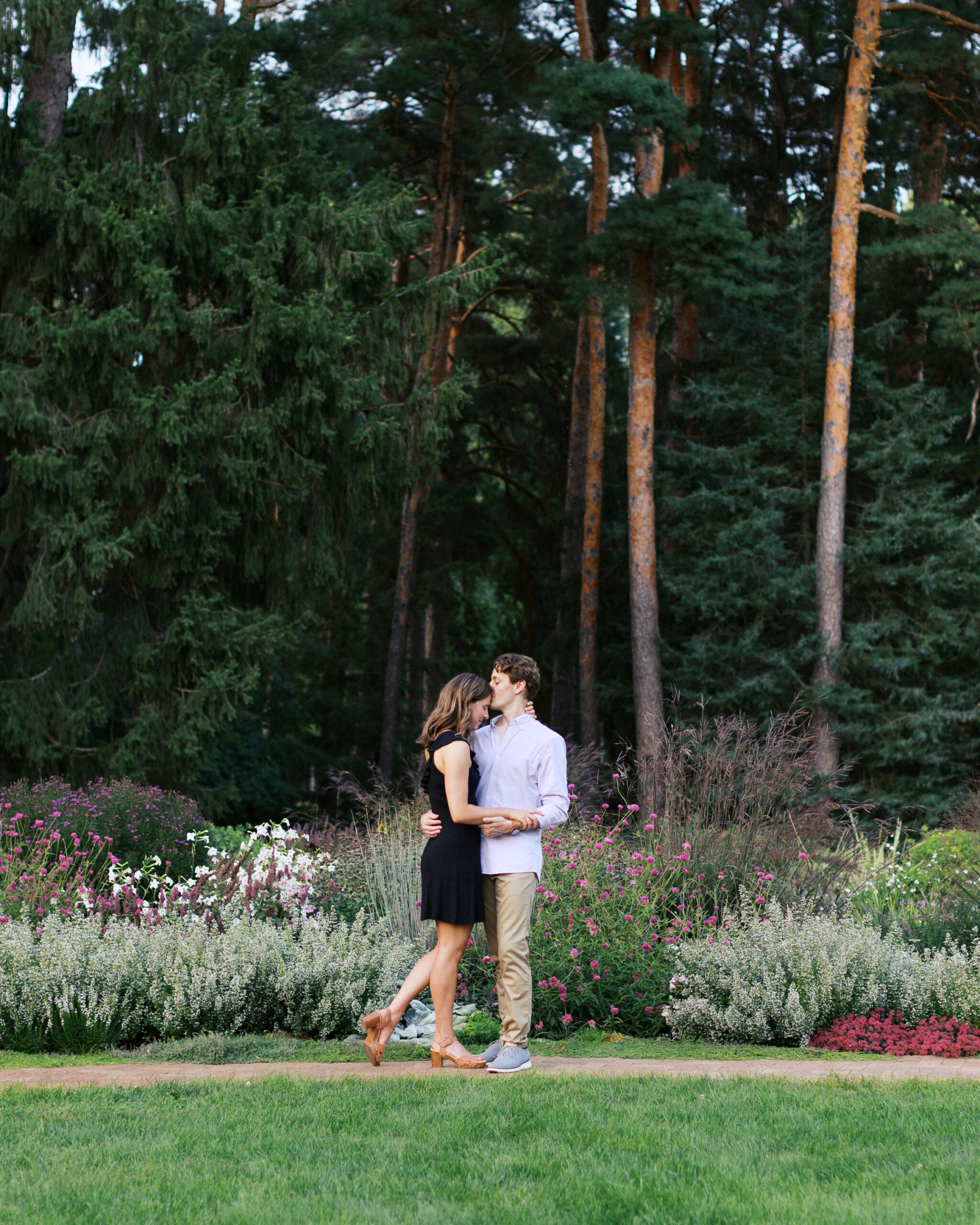 A romantic moment at Noerenberg Gardens in Orono—Matthew gently kisses Katherine on the forehead, surrounded by lush greenery. Captured by Toly Dzyuba Photography.
