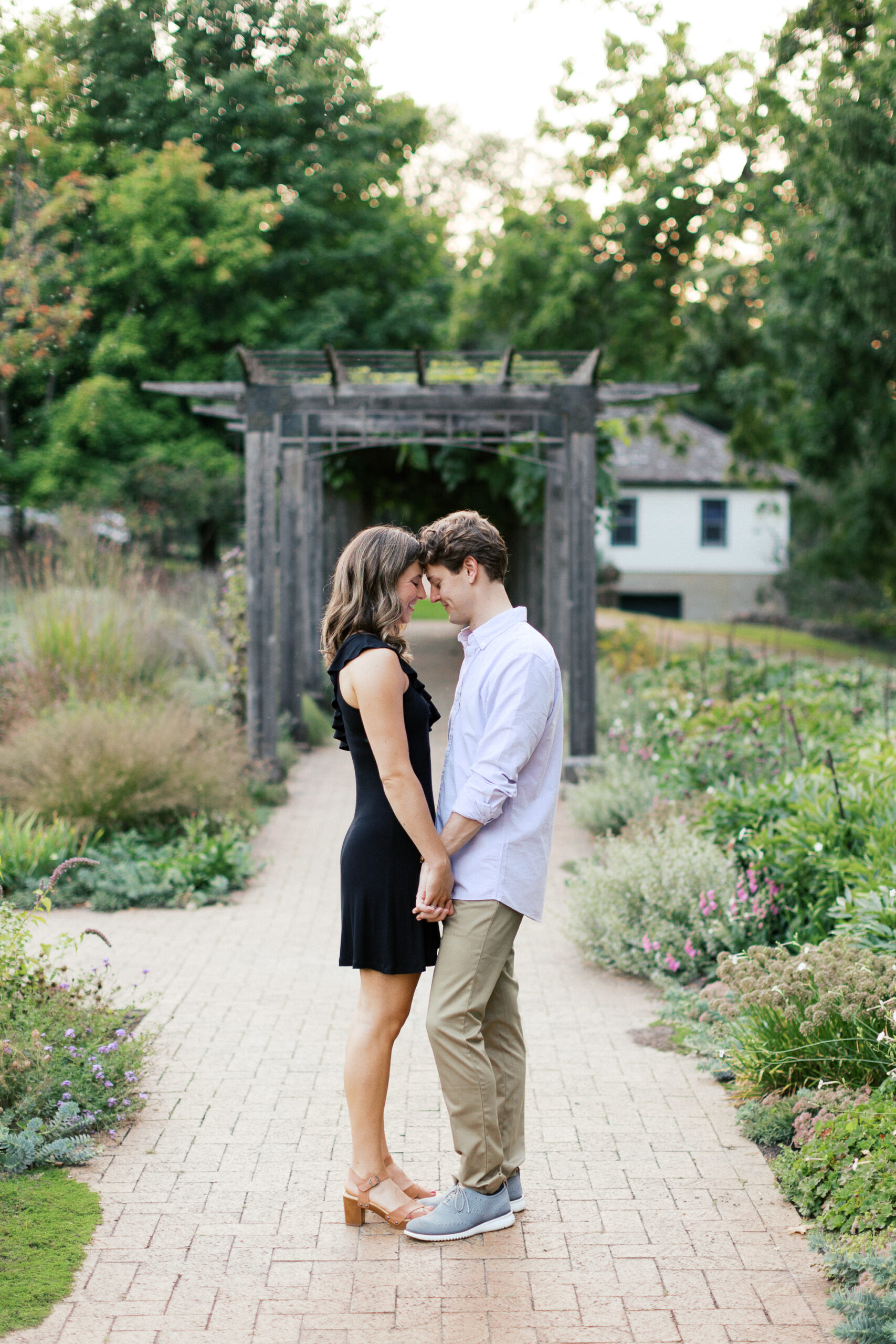 Couple touching foreheads and smiling while holding hands at Noerenberg Gardens in Wayzata. 