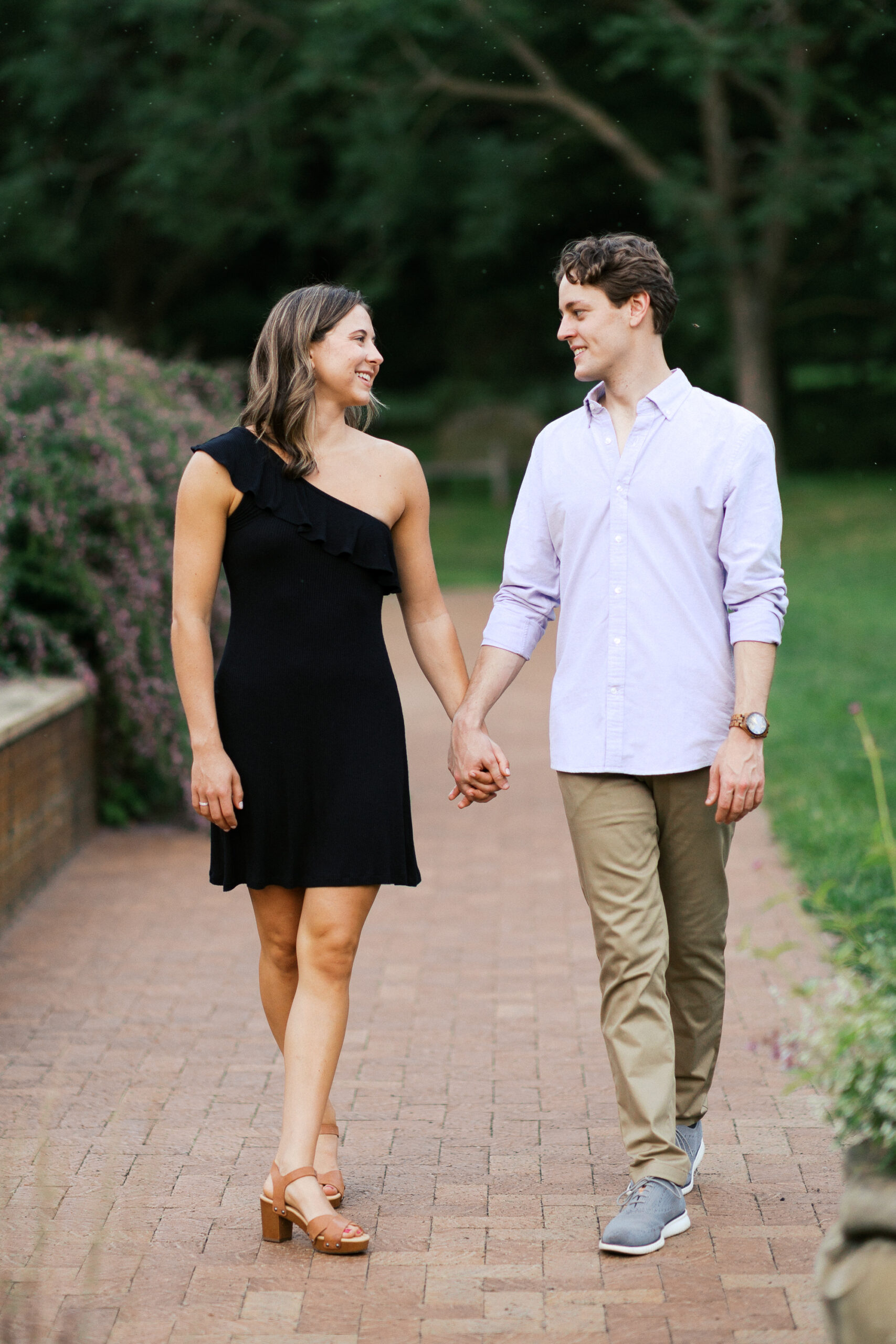 Couple looking at each other smiling and walking holding hands in Orono, MN.