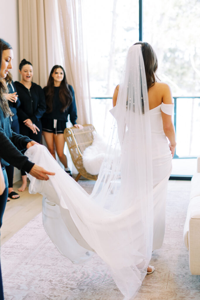 A photo of the bride's bridesmaids who are holding her dress train. The photo was taken at Catalyst at Nature Link in Nisswa, Minnesota. This is the location of the bride and groom's wedding.