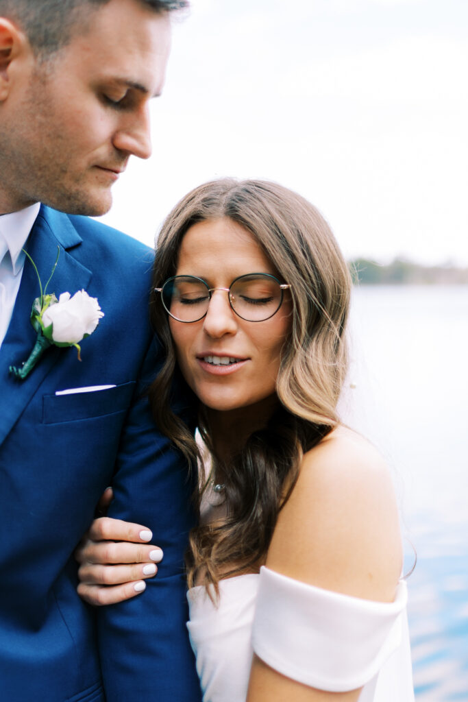 Bride is leaning on her groom's shoulder while he looks over her in awe.