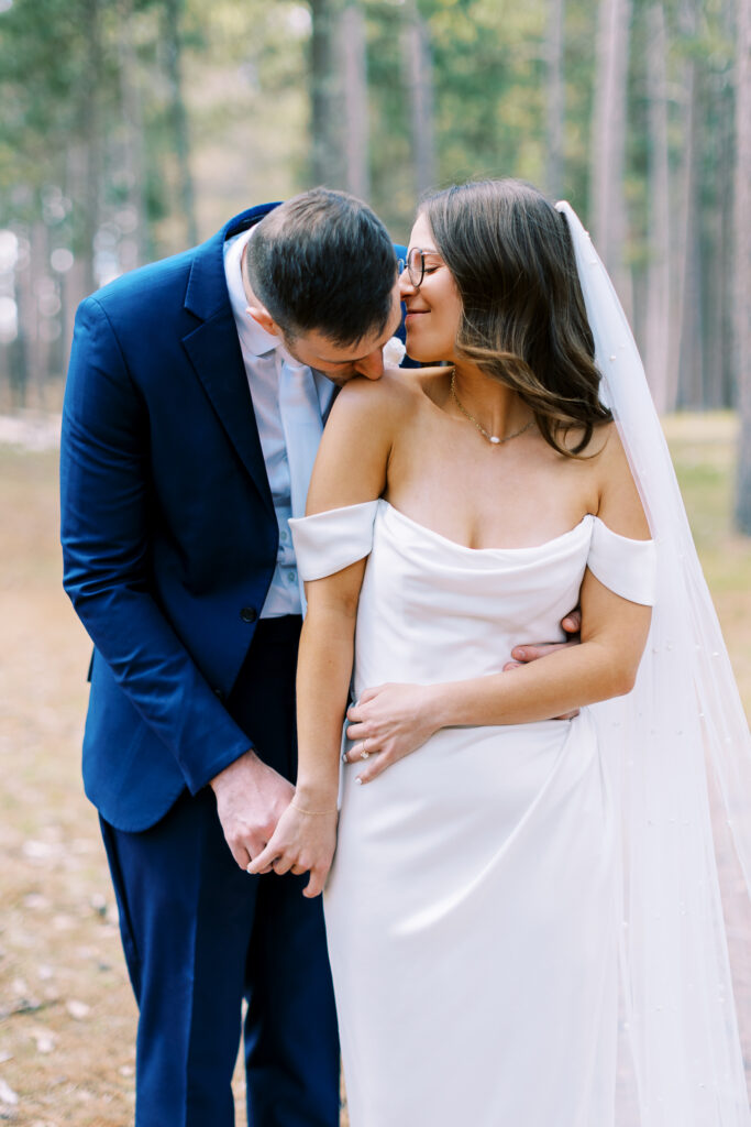 Groom kissing her shoulder with a gentle kiss. 