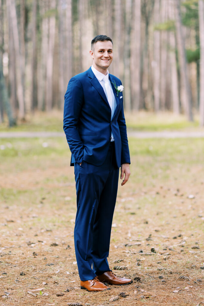 Groom in the blue suite standing tall looking in the camera for a photo.
