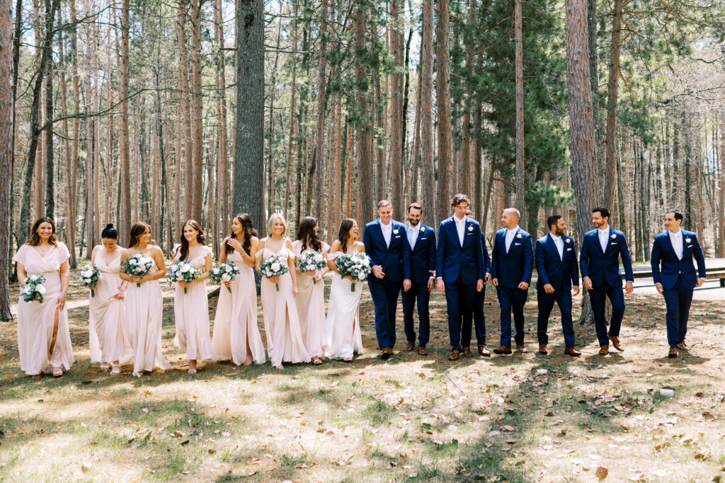 Bridesmaids and groomsmen are all walking together and laughing.