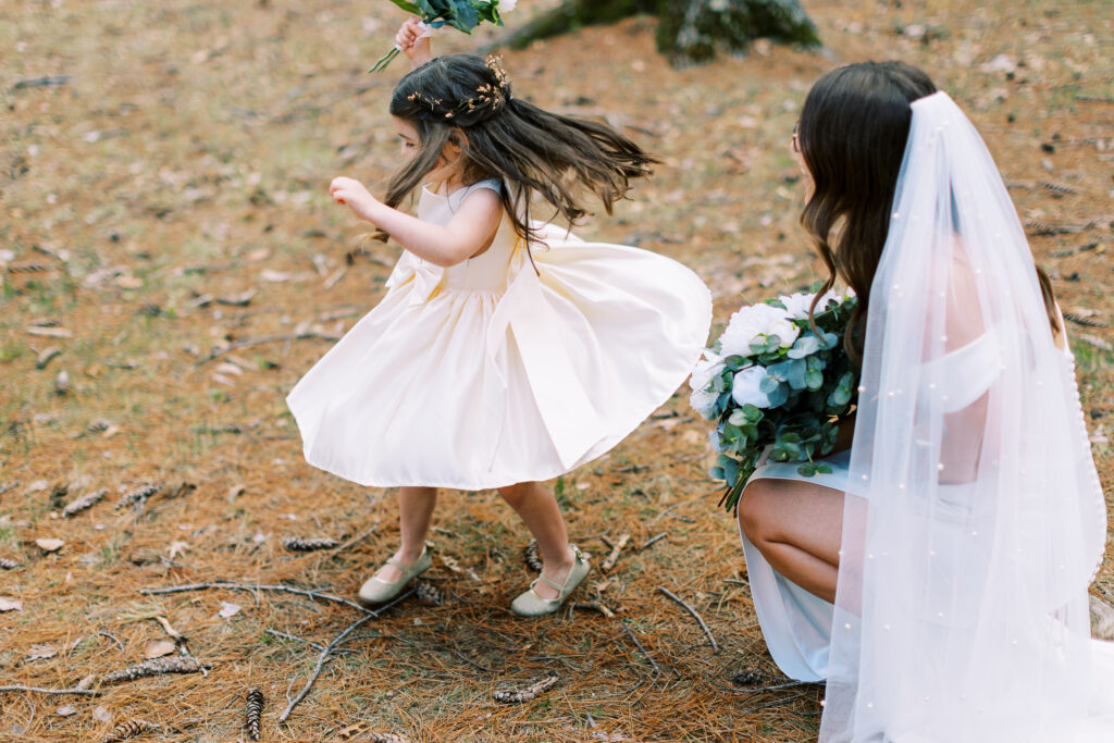 Flower girl is twirling her dress while the bride is watching.