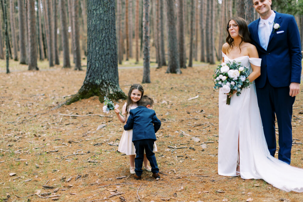 Flower girl is getting hugged by her brother the ring boy. 