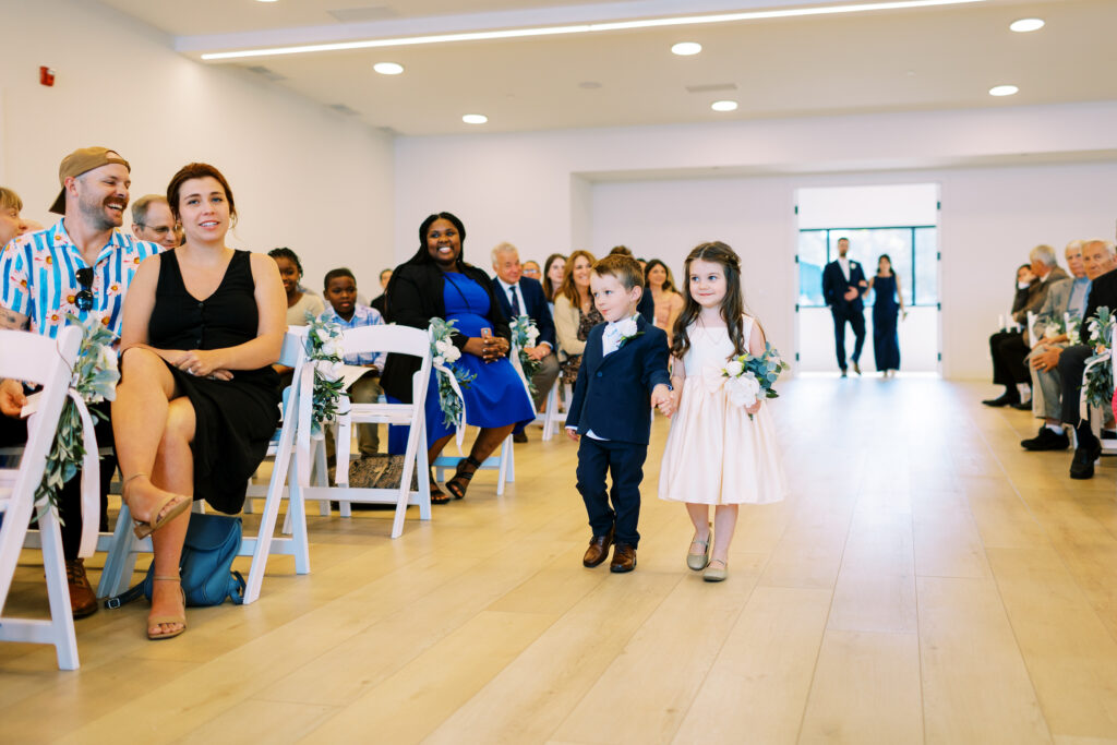 The flower girl and ringbearer walks down the aisle.