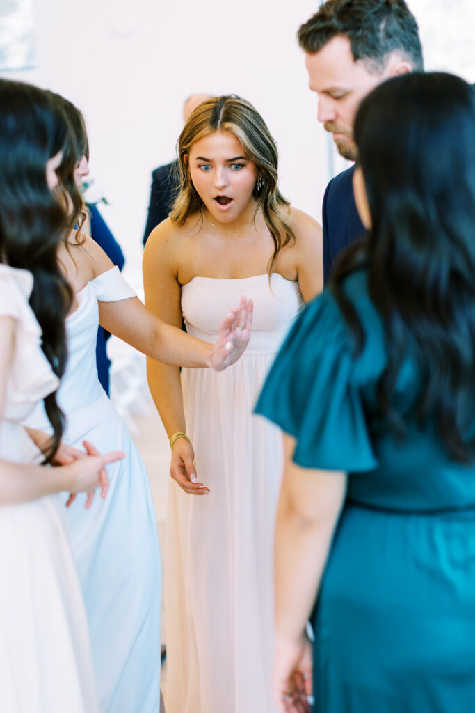 The Bridesmaid is looking at Bride's wedding ring and is in shock how beautiful it is.