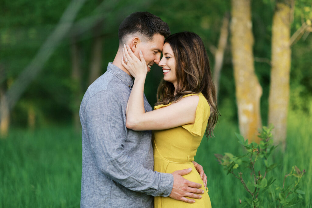 Couple touches noses together with her hands on his face as they share a moment with a smile.