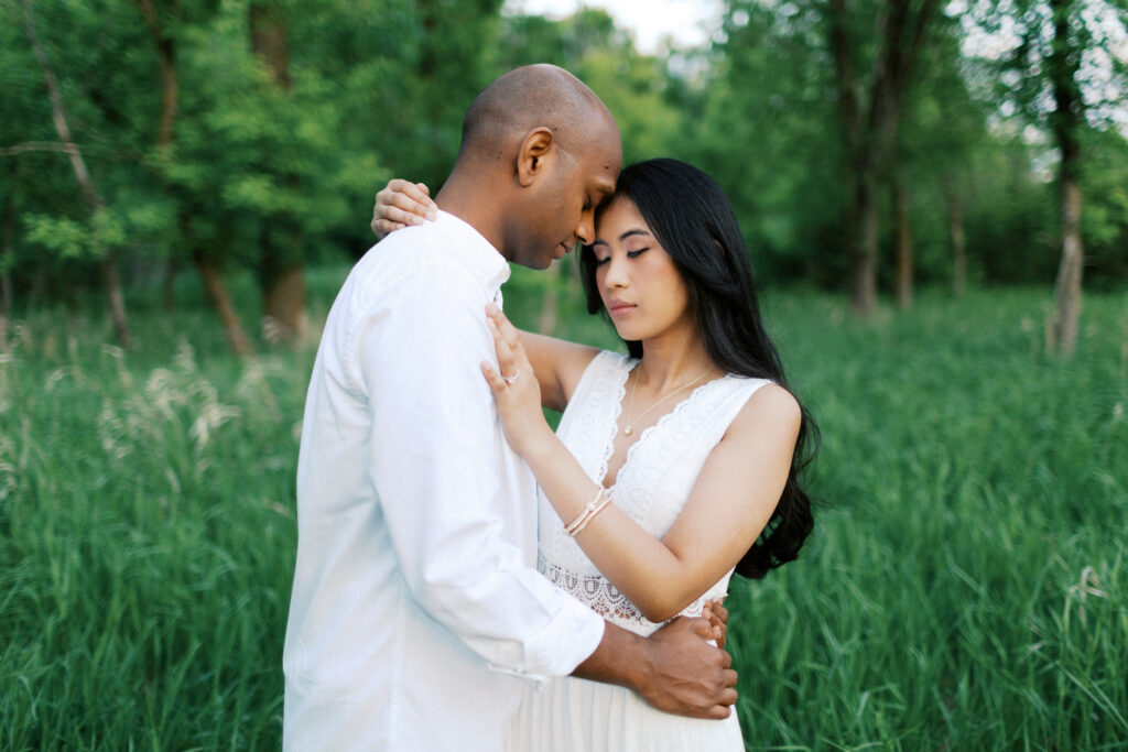She has her arm over his shoulder as they gently rest their heads together, sharing an intimate moment.