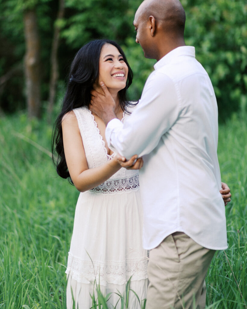 He places his hand on her face, laughing joyfully, capturing a moment of love and happiness.
