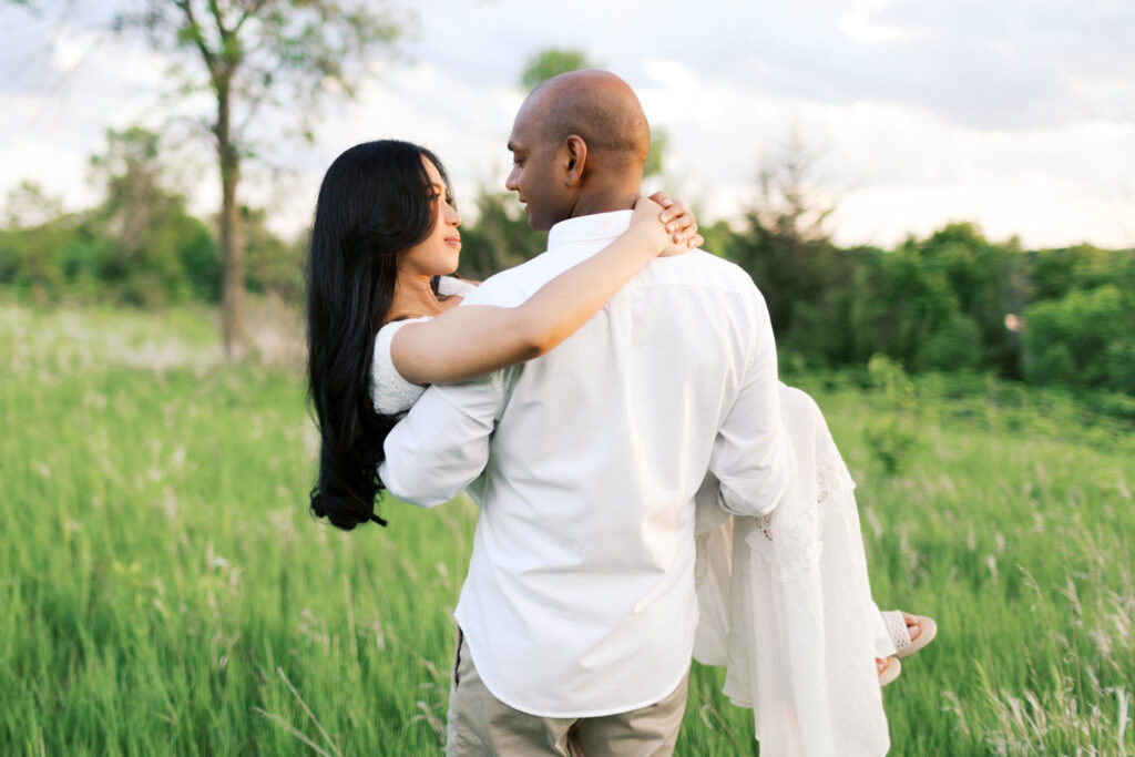 He lifts her in his arms, holding her close to his heart as they look into each other’s eyes, bathed in the golden sunset at Elm Creek Park in Maple Grove. Captured by Minnesota wedding photographer Toly Dzyuba.