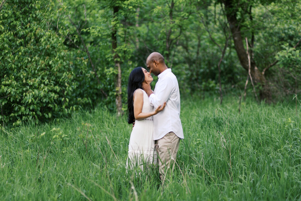 A fine art image of the couple touching noses, smiling as she places her hand on his elbow and he gently touches her face, capturing a tender and joyful moment.