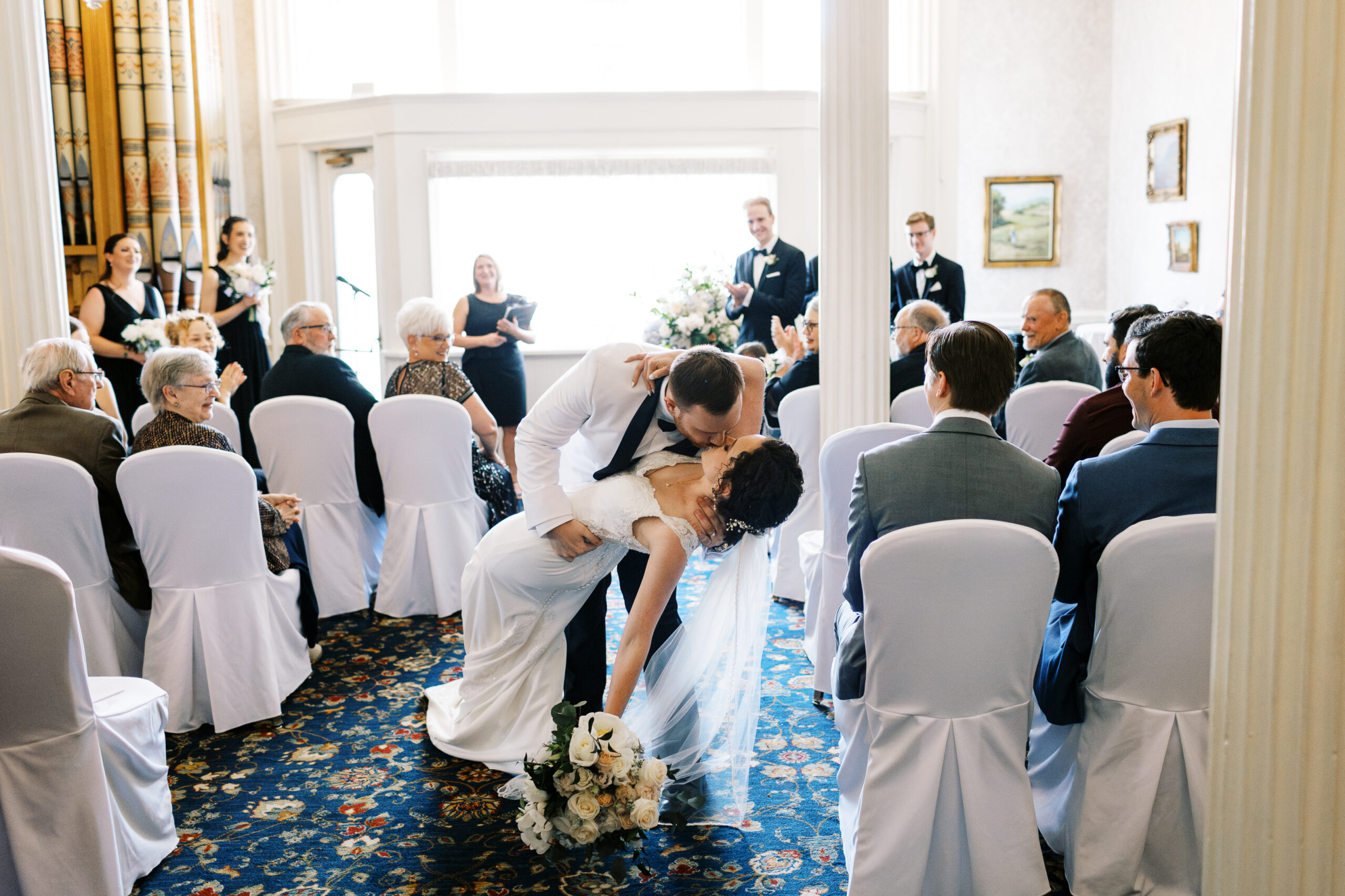 Groom dips his bride and kisses her as the crowd cheers after they say “I do” at the St. James Hotel in Red Wing, captured by a Minnesota wedding photographer.