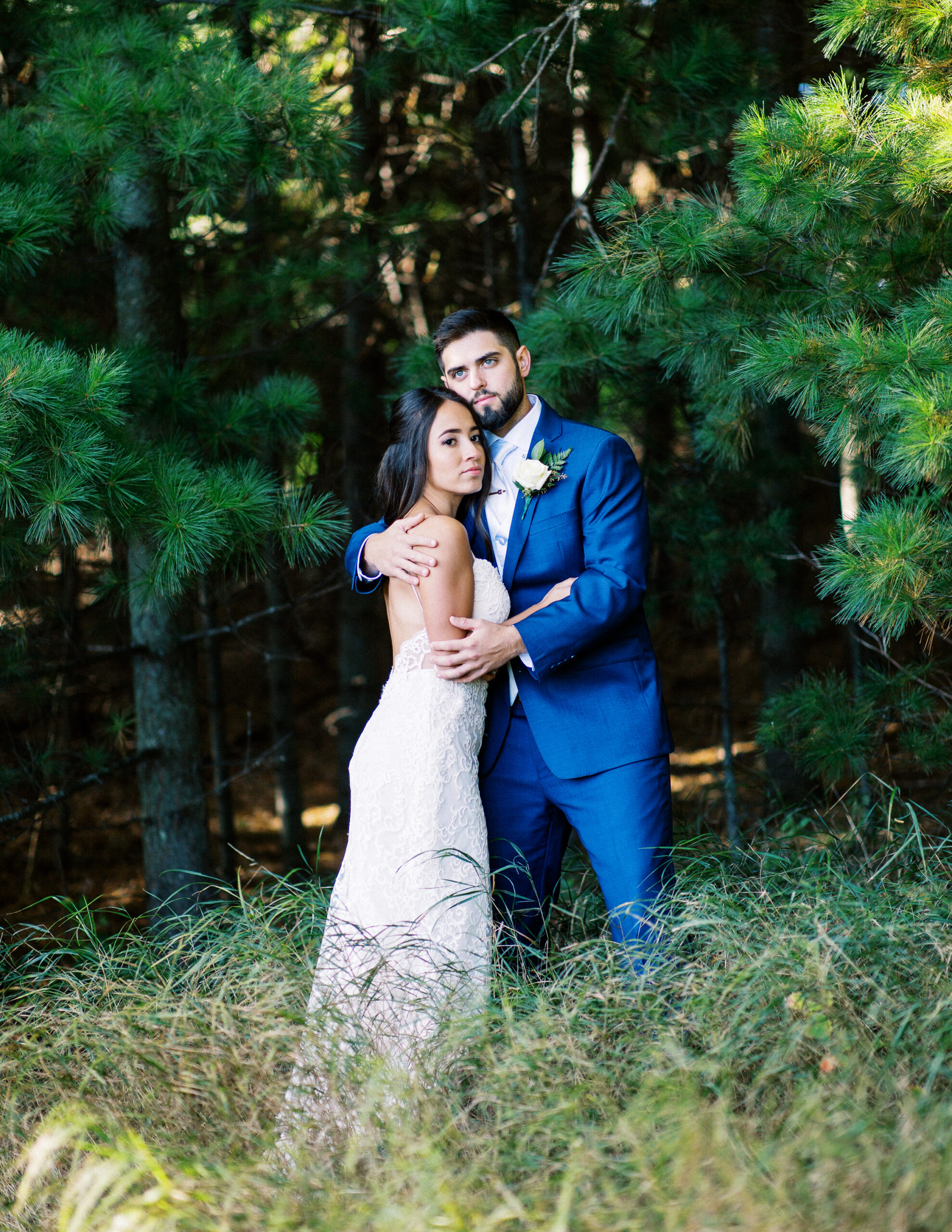 Bride and groom in the embrace of nature, with the tall pine trees behind them, looking out at the horizon. Captured by Minnesota wedding photographer, Toly Dzyuba.