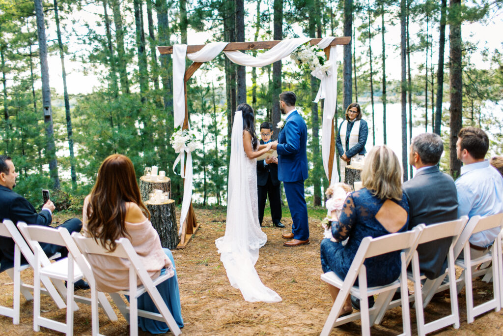 Bride and groom hold hands and listens to the scripture while the boy reads at their wedding ceremony.