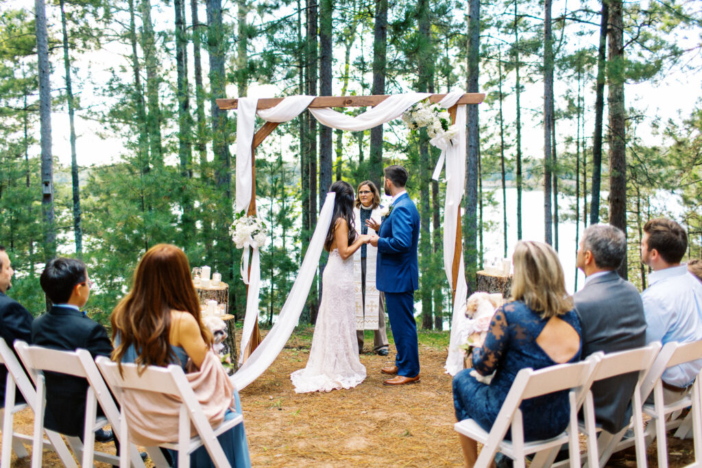 Wedding ceremony with bride and groom holding their hands in the beautiful nature and receiving a blessing.