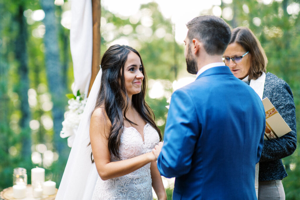 Bride with joy looks into his eye during the wedding ceremony in Webster, WI. Captured by Toly Dzyuba, Minnesota wedding photographer.