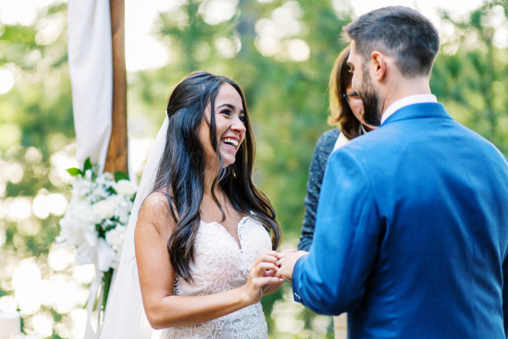 Bride and groom exchange their rings at a Lakeside Ceremony Surrounded by Love.