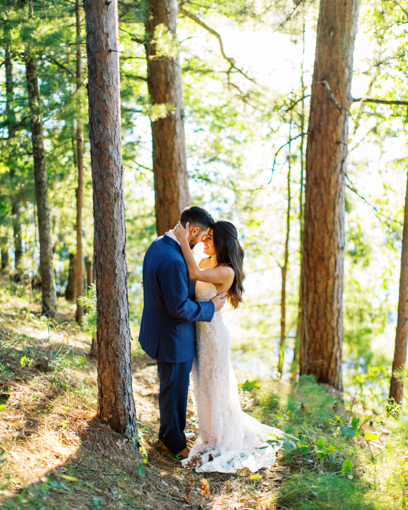 Bride and groom puts heads together in the moment as they stay still in the moment of joy. This scene occurred during a heartwarming cabin elopement in Webster, WI captured by a Minnesota Wedding Photographer.