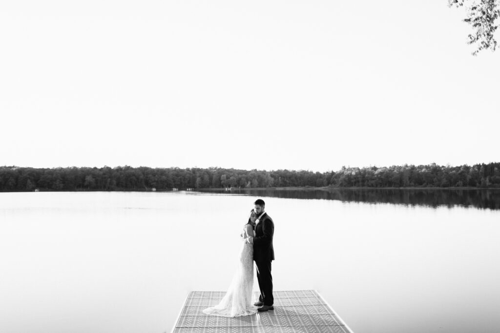 Newlyweds hugging on the dock on the lake. A heartfelt Cabin Elopement in Webster, WI | Minnesota Wedding Photographer.