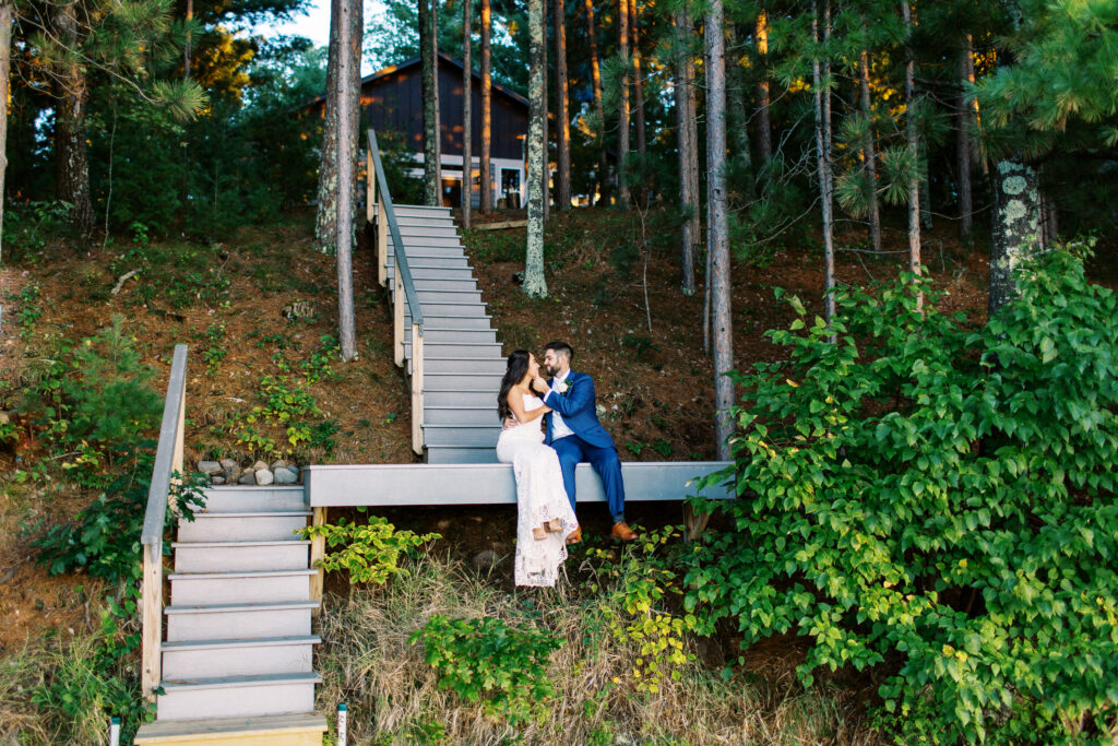 Bride and groom sitting by their cabin on the dock soaking in the sunset looking at each other with joy. A true heartfelt Cabin Elopement in Webster, WI | Minnesota Wedding Photographer.