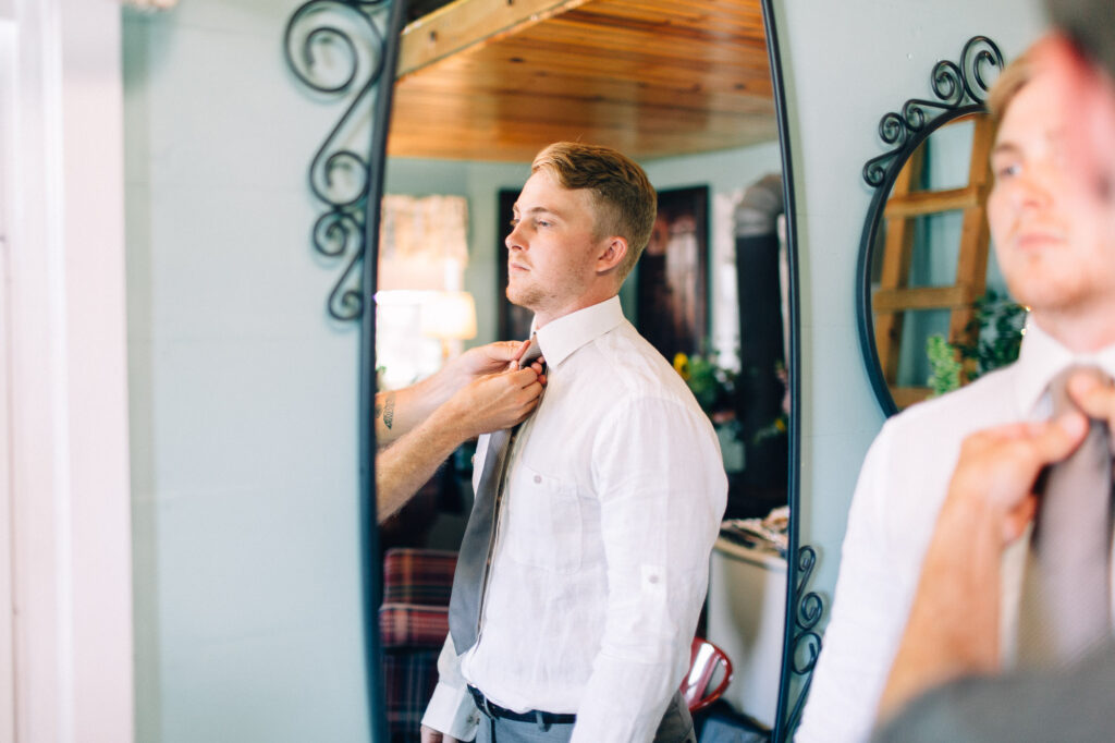 Groomsman helping the groom with his tie at Legacy Hill Farm.