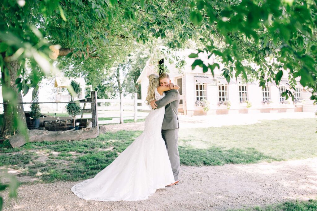 Groom embraces his bride with joy during their first look at Legacy Hill Farm, captured by Minneapolis wedding photographer.