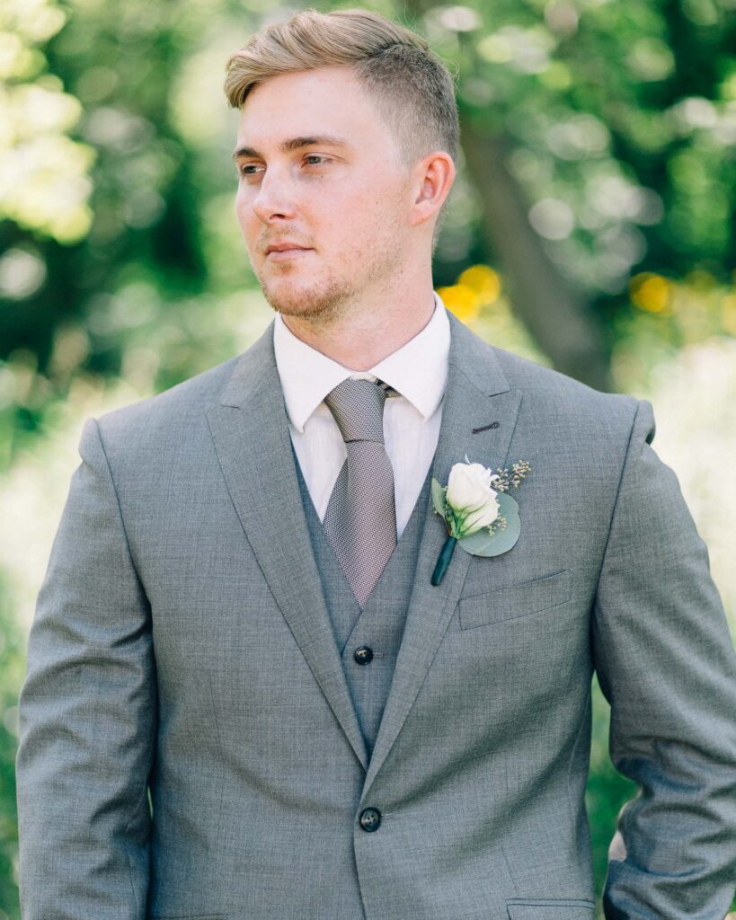 Groom in his suit looking away as he poses for a photo.