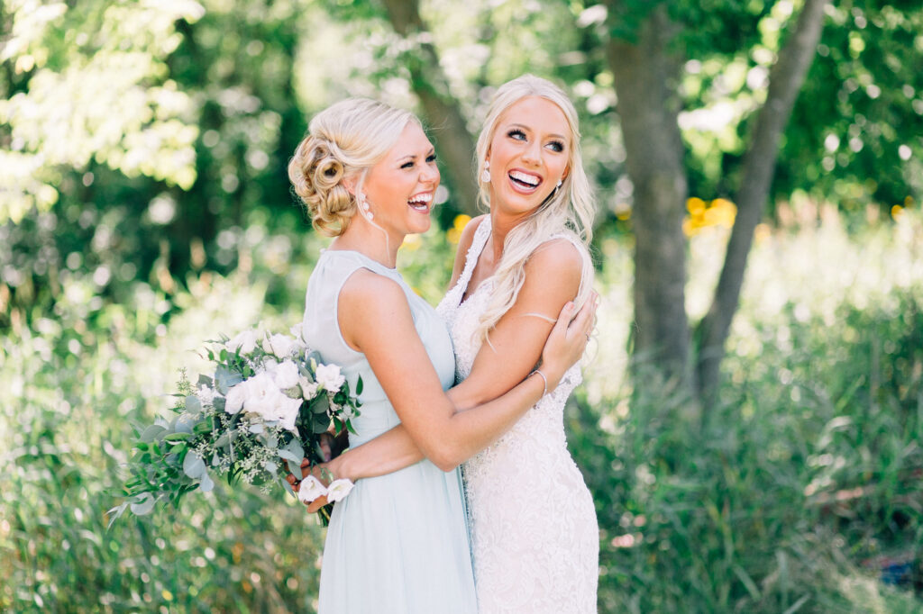 Bride and her bridesmaids laughing hysterically and hugging each other.