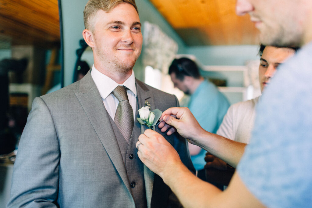 Groom getting his boutonniere pinned onto his jacket at Legacy Hill Farm.