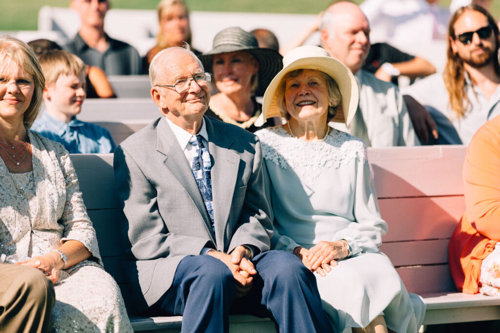 Older couple sitting together at the wedding ceremony, smiling at Legacy Hill Farm.