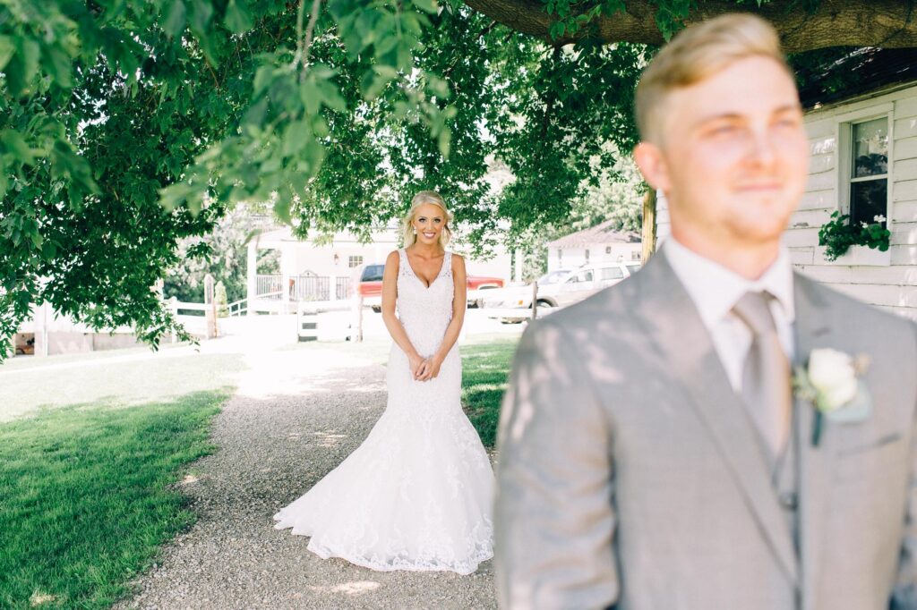 Bride approaches her groom from behind during their first look at Legacy Hill, capturing the excitement of the moment.