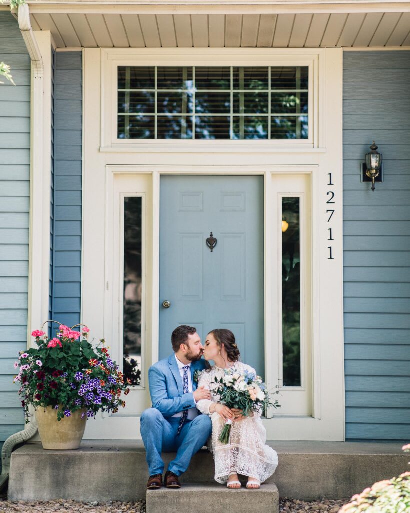Bride and groom sitting on their porch kissing at the summer backyard wedding in Minneapolis.