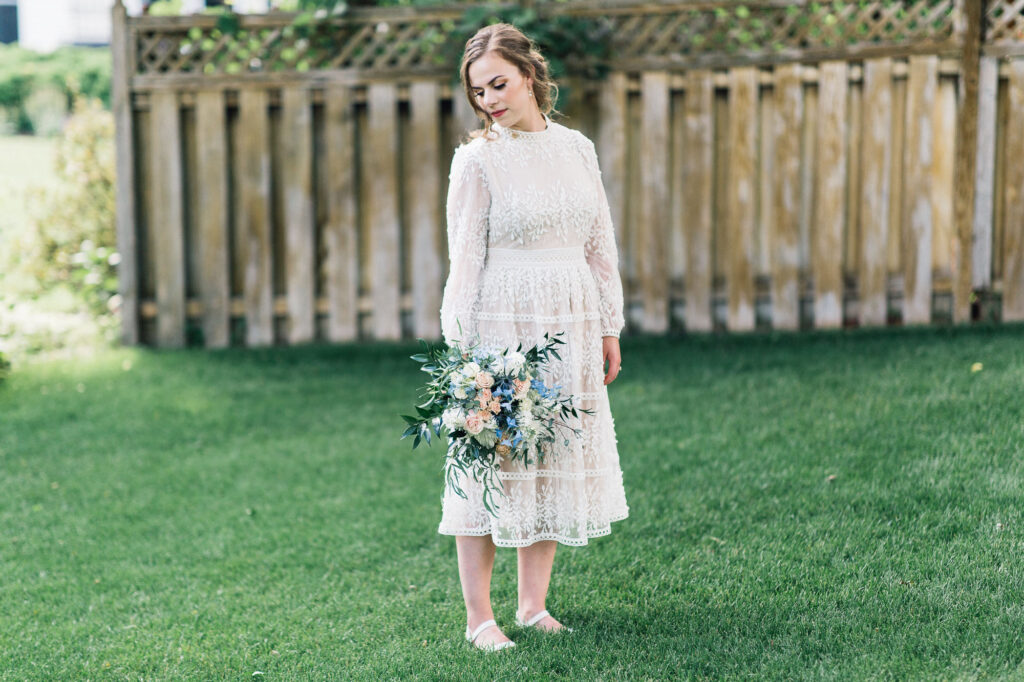 Bride gazing away while holding a delicate bouquet of fresh flowers.