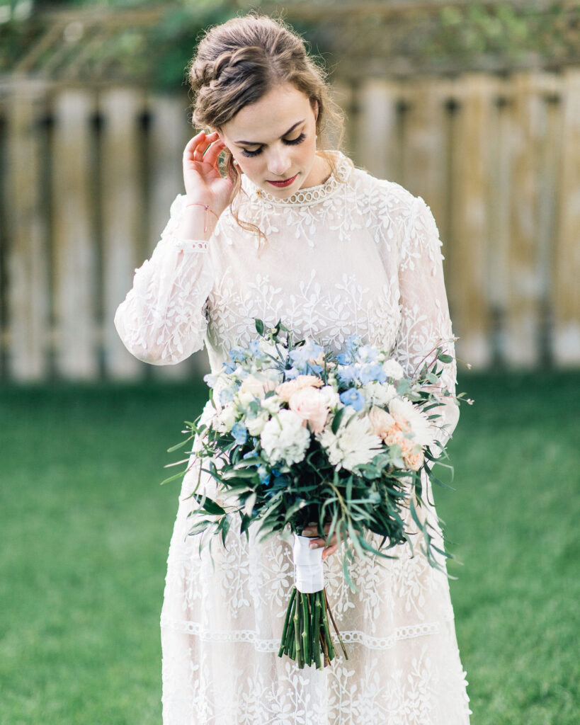 Bride looks at her gorgeous flowers at the summer backyard wedding in Minneapolis.