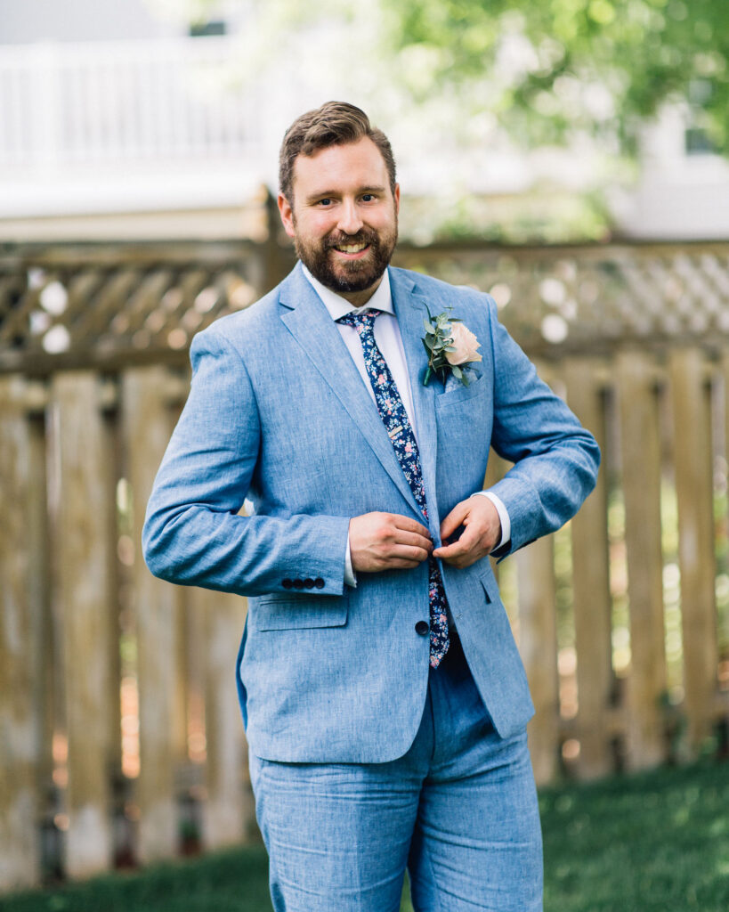 Minneapolis groom smiling as he buttons his blue suit jacket.
