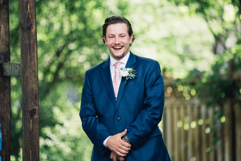 A smiling groomsman at the summer backyard wedding in Minneapolis.