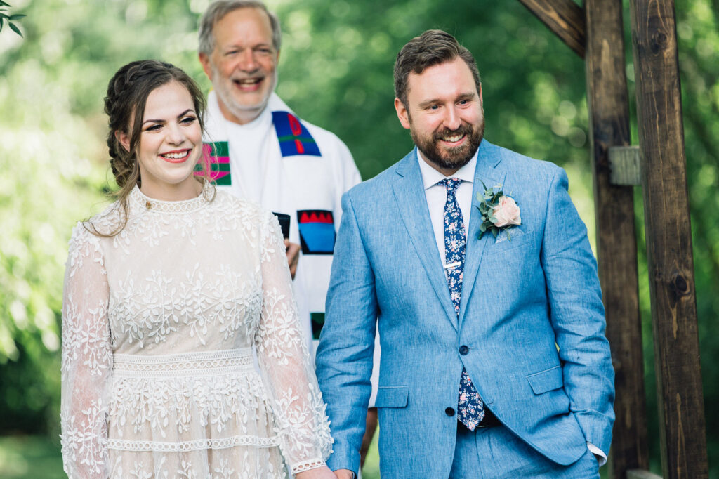 Bride and groom smiles at the summer backyard wedding ceremony.