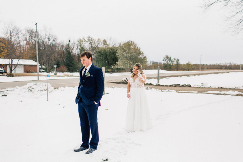 Bride approached her groom for the first look on a snowy winter day, wiping her tears at The Cottage Farmhouse.