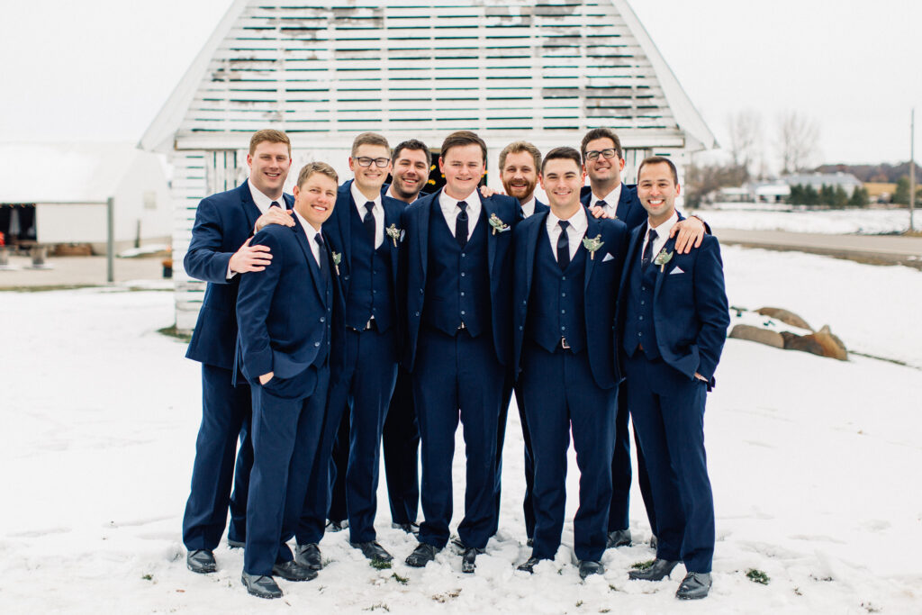Groomsmen smiling with arms around each other at The Cottage Farmhouse, captured by Minnesota wedding photographer.