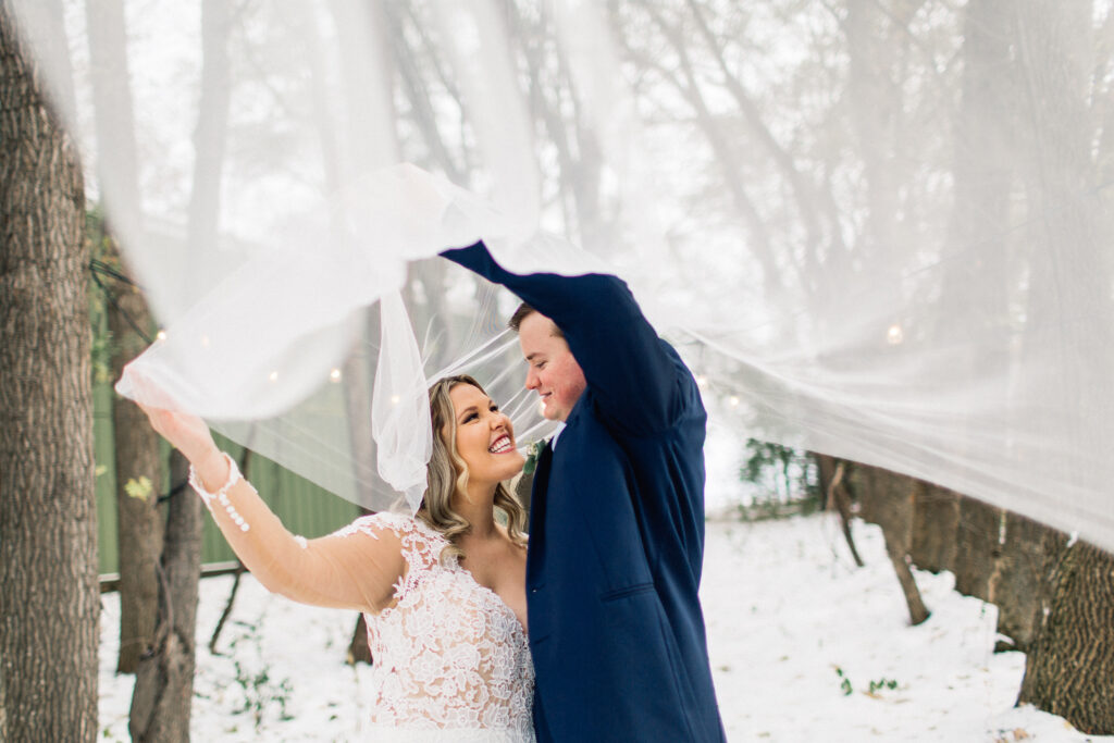 Bride and groom under the vail smiling at The Cottage Farmhouse winter wedding.