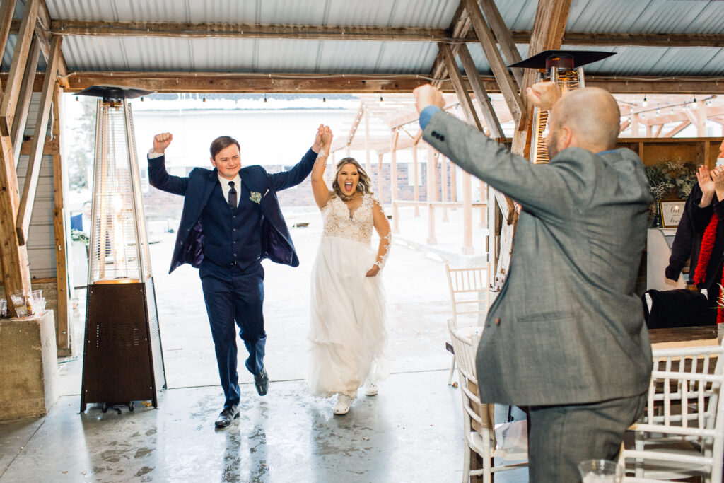 Bride and groom entering the reception barn with the the grand entrance celebration, captured by a Minneapolis wedding photographer at The Cottage Farmhouse.