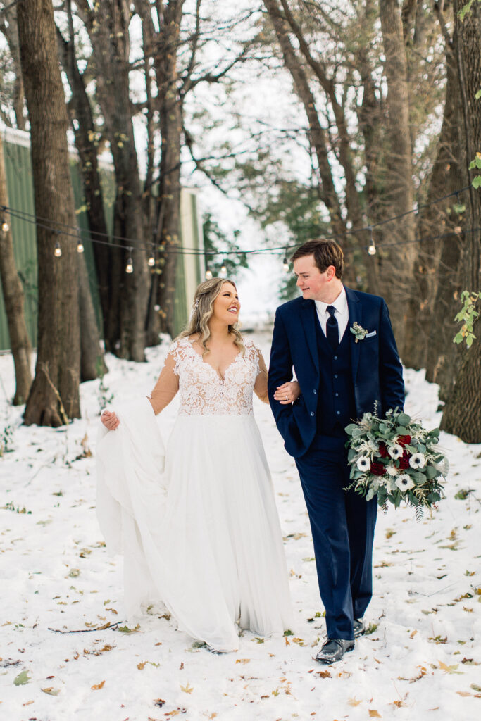 Bride and groom walking together looking at each other and smiling at The Cottage Farmhouse winter wedding.