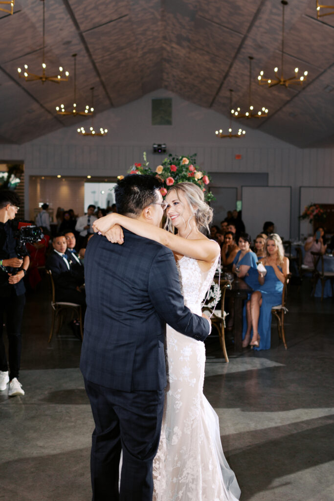 Newlyweds sharing their first dance beneath chandeliers at The Hutton House wedding venue in Minneapolis as they look in each other eyes with love, captured by Minnesota wedding photographer Toly Dzyuba Photography