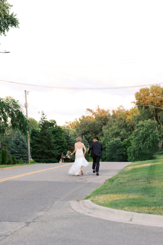 Bride and groom running joyfully on a Minneapolis street during their wedding day, captured by Minnesota wedding photographer Toly Dzyuba Photography