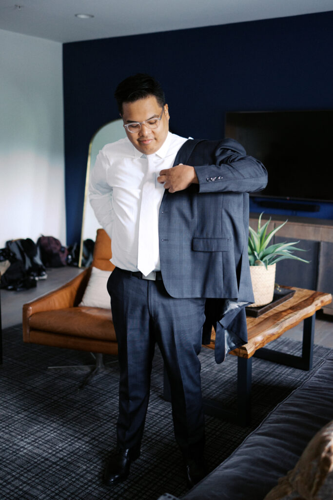 Clean, bright, and timeless image with groom putting on his jacket at the Hutton House in Minneapolis, captured by the best Minneapolis wedding photographer Toly Dzyuba Photography.