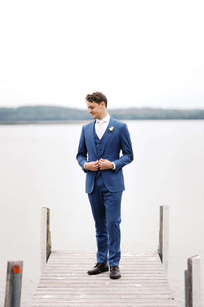 groom posing on the dock looking away with his hands slightly on the jacket at Madden's resort.