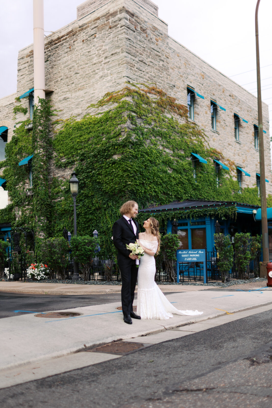 Newlyweds in downtown Minneapolis next to Nicollet Island Inn standing together and looking at each other with ultimate joy, captured by Minneapolis Fine Art Wedding Photographer.