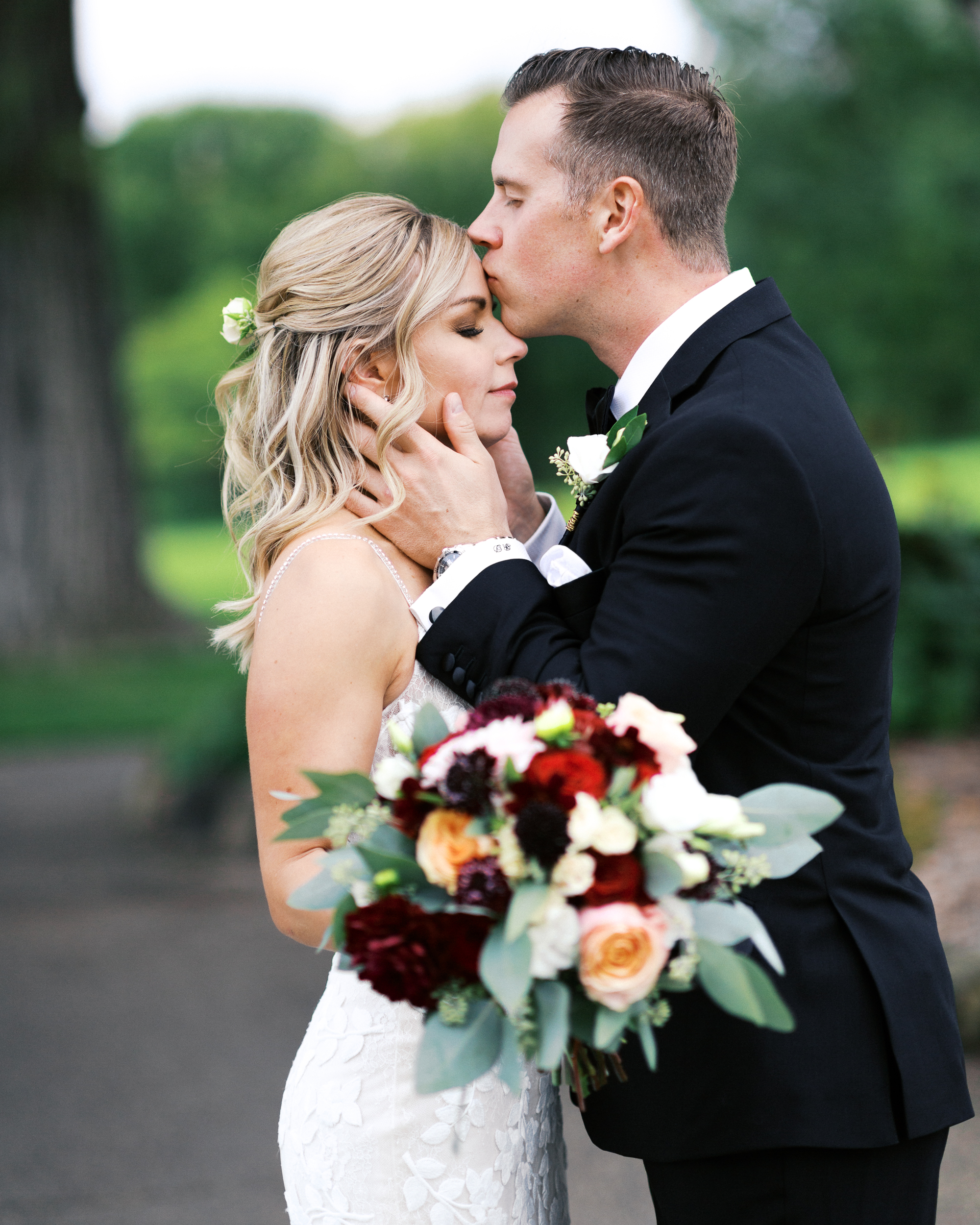 Groom kisses his Bride in the forehead while she closes her eyes at Minneapolis Golf Club, captured by Toly Dzyuba Photography.